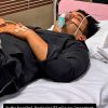 Man lying in hospital bed with an oxygen mask and IV tubing, resting with eyes closed.
