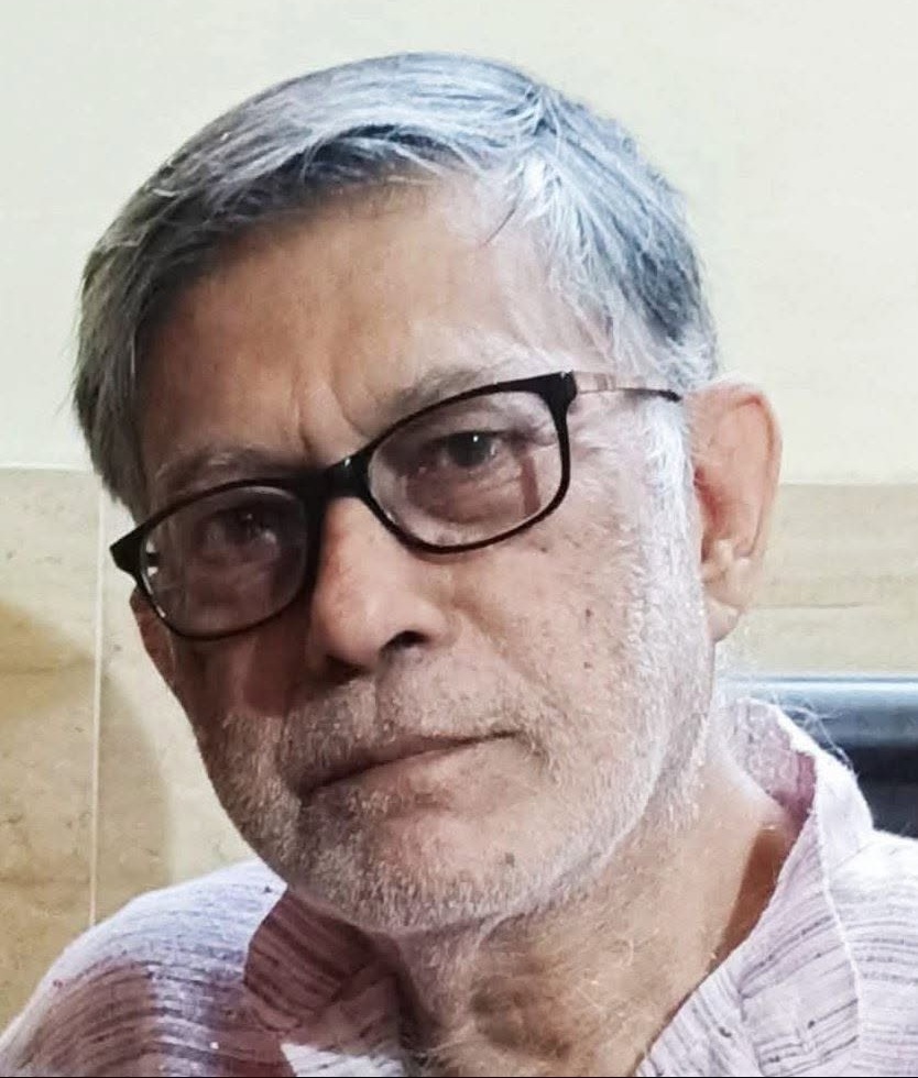 tadit kumar | No. 1 Indian Media News Portal Older man with gray hair and black glasses, wearing a light pink striped shirt, looking at the camera.
