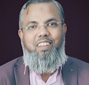Portrait of a smiling man with a gray beard and glasses, wearing a pink shirt and dark blazer.