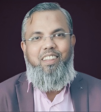 Portrait of a smiling man with a gray beard and glasses, wearing a pink shirt and dark blazer.