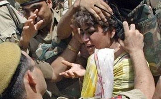 Young boy surrounded by soldiers, distressed as a few hands hold him by the head amid a tense scene
