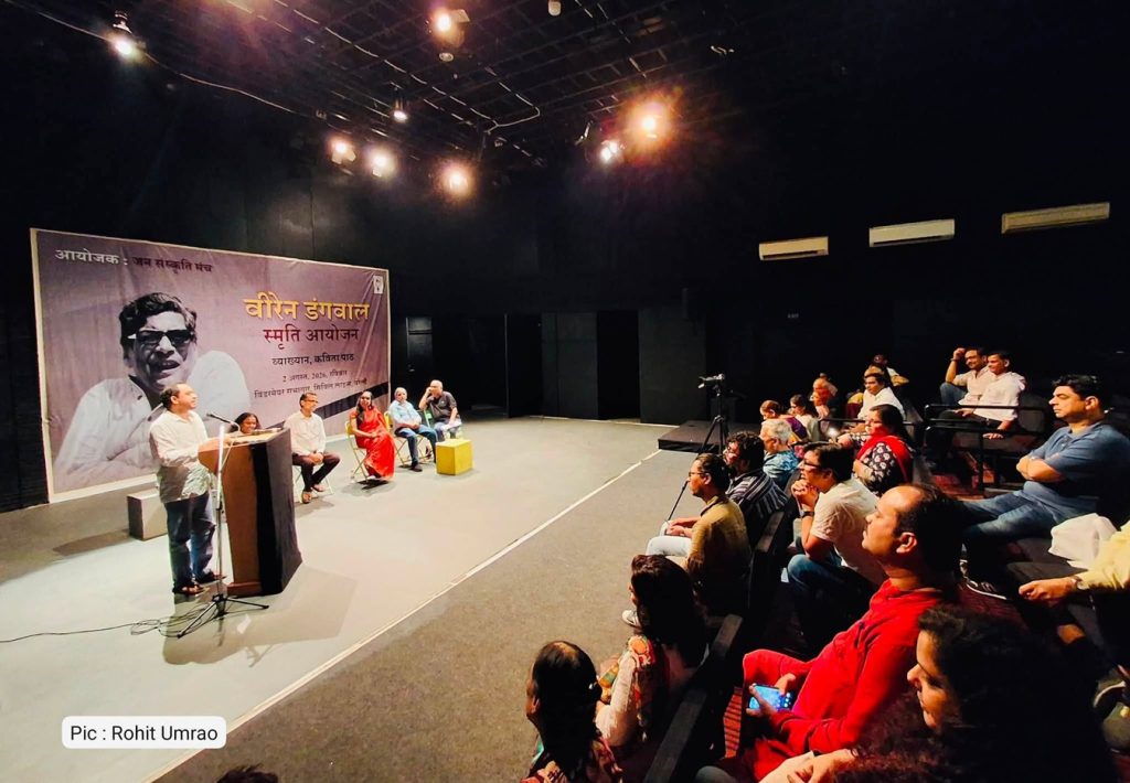 viren ji | No. 1 Indian Media News Portal Panel discussion on stage with speakers seated, banner in Hindi behind them, audience watching in a theater setting.