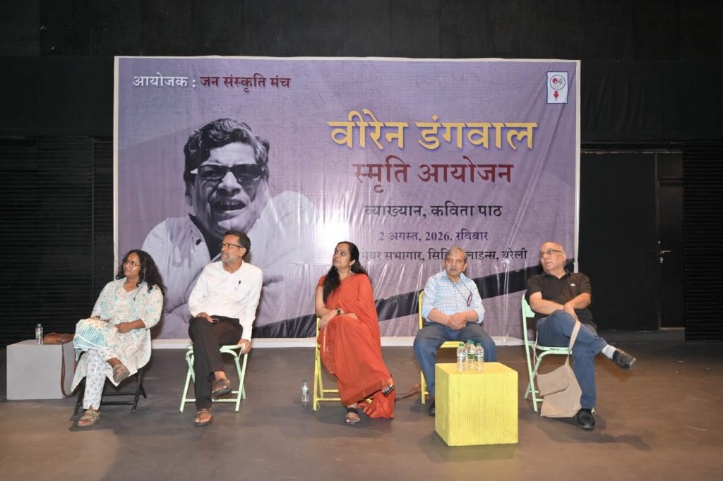 viren ji_2 | No. 1 Indian Media News Portal Panel discussion on a stage with five people seated in front of a large purple banner, likely a literary event poster in Hindi/Marathi; individuals appear to be speakers or panelists.