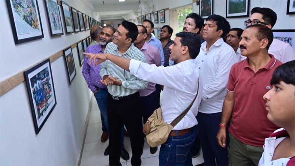world photography_2 | No. 1 Indian Media News Portal Group of men in a hallway gallery looking at framed photographs on the wall as one man points to a piece.