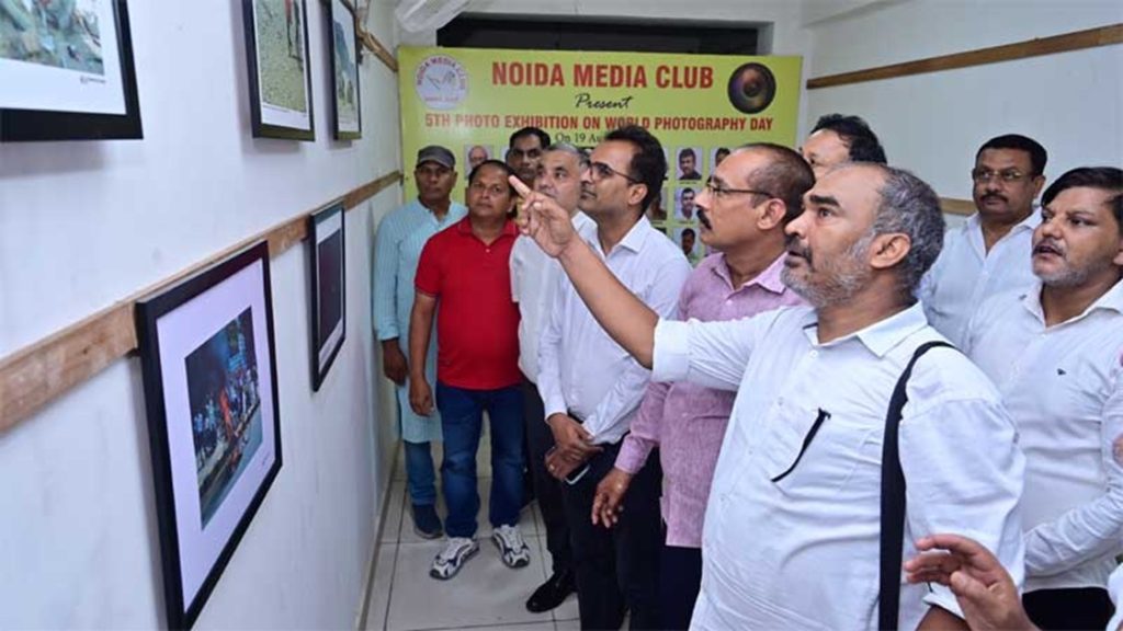 world photography_3 | No. 1 Indian Media News Portal Group of men in a gallery viewing framed photographs on the wall during a photo exhibition, with a Noida Media Club banner in the background