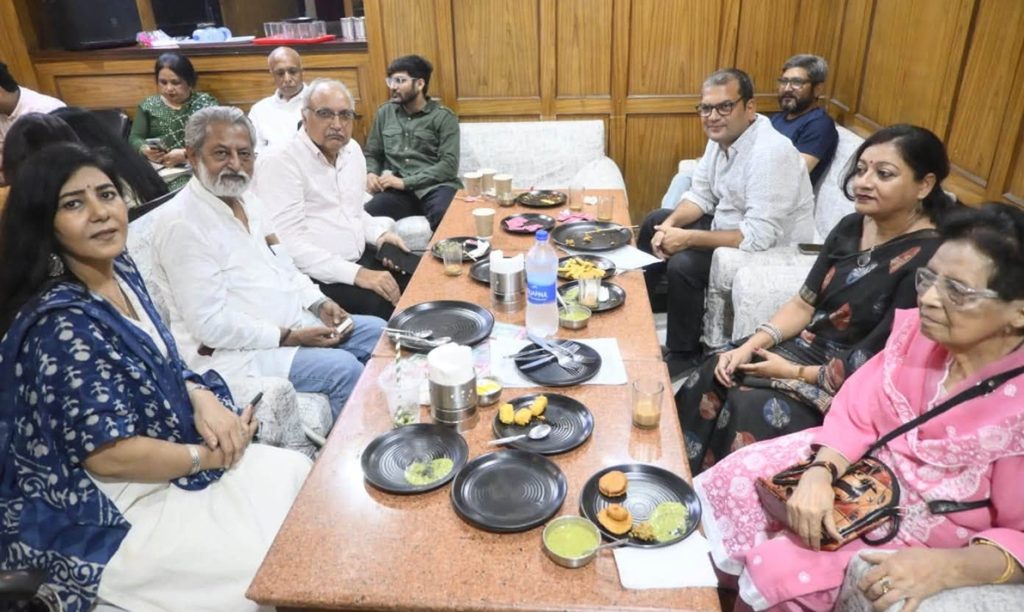 yash_pci | No. 1 Indian Media News Portal A group of people seated around a long table with food and drinks, socializing in a casual dining room.