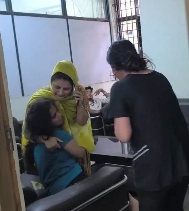 4pm_delhi | No. 1 Indian Media News Portal Woman in a yellow hijab comforts a crying child who is being hugged by another woman in a clinic waiting room as a staff member approaches.