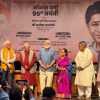 Eight people stand on a stage for a commemorative event, with a large banner announcing '95th Jayanti' in Hindi behind them.