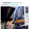 Bearded man in a light shirt stands on a busy city street beside a large mural portrait of a man, with screenshots of tweets about his return above.