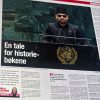 Man in a black suit and hat speaks at a United Nations podium with a large black banner reading 'En tale for historie-bøkene' in the foreground (news photo).