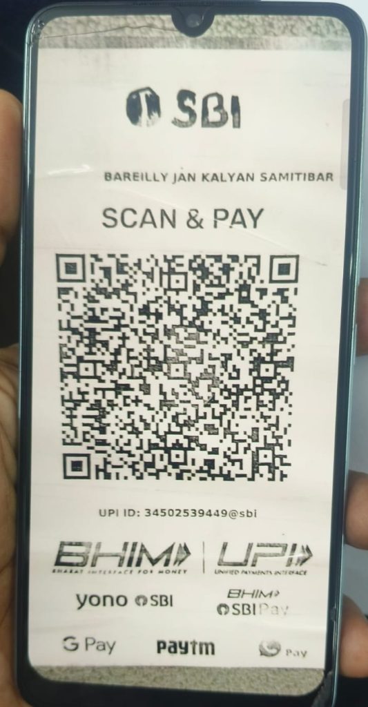 Smartphone screen showing an SBI Scan & Pay QR code for UPI payments, with logos at the bottom and the UPI ID displayed.
