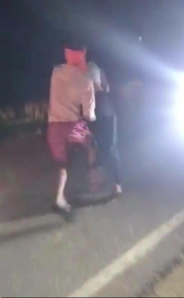 bihar_2 | No. 1 Indian Media News Portal Two people standing on a dark road at night, one in a tan jacket and red shorts facing away from the camera.