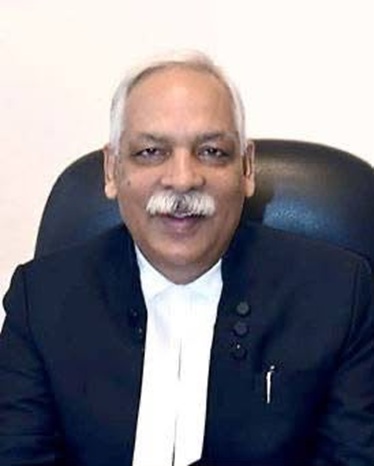 dk upadhyay | No. 1 Indian Media News Portal Smiling man with white hair and mustache, in a dark suit and white shirt, seated in a black office chair.