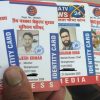 A hand holding several press identity cards with photos and Hindi text visible on each card.