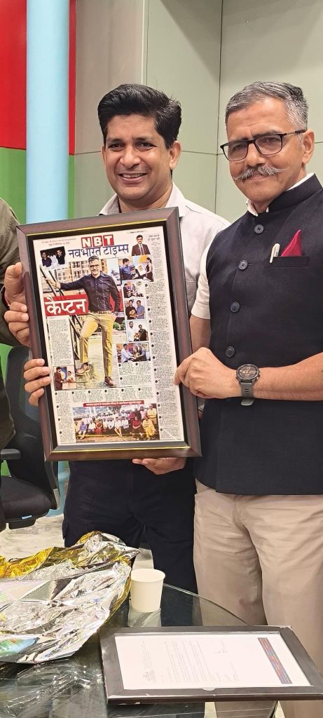 img_0827 | No. 1 Indian Media News Portal Two men pose in an office, one holding a framed front page of a newspaper titled NB T/Nav Bharat Times showing a man in yellow pants on the cover.