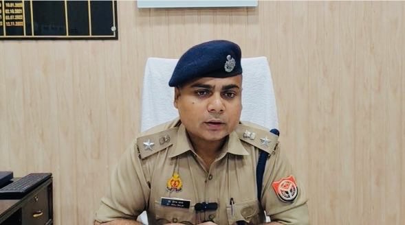 Police officer in khaki uniform with beret, seated at a desk in an office.
