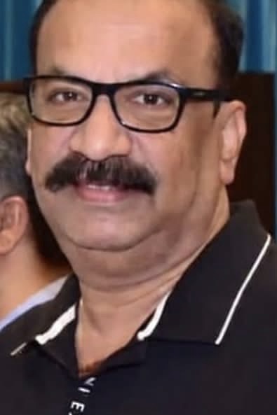 Close-up portrait of a middle-aged man with a mustache, black-framed glasses, and a black polo shirt.