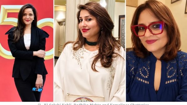 Three women posing at an event: Sakshi Kohli (left) in a black suit, Radhika Mehta (center) in a white embellished top, Kamalinee Chatterjee (right) in a blue lace top with red glasses.