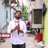 Mohammad Irfan, a The Wire reporter, stands in a narrow alley holding a microphone in a white shirt.
