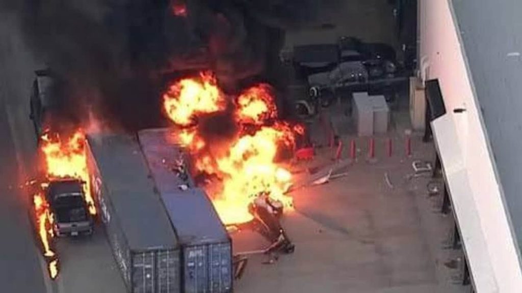 nbc crash | No. 1 Indian Media News Portal Port or dock area with a large fire and black smoke; flames surround a truck and shipping containers as a person runs away and debris lies nearby.