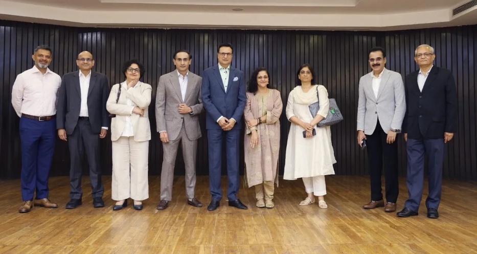 nbda | No. 1 Indian Media News Portal Nine professionals in business attire pose for a group photo in a room with a dark wood-paneled wall, on a wooden floor.