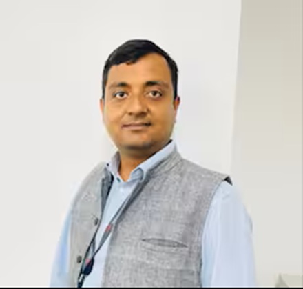 rajeev kamal | No. 1 Indian Media News Portal Man in a light blue shirt and gray vest posing for a professional photo indoors.