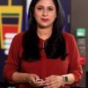 Female news anchor in a red blouse stands in a studio, holding a small device, CNBC TV18 logo in the top-right corner.