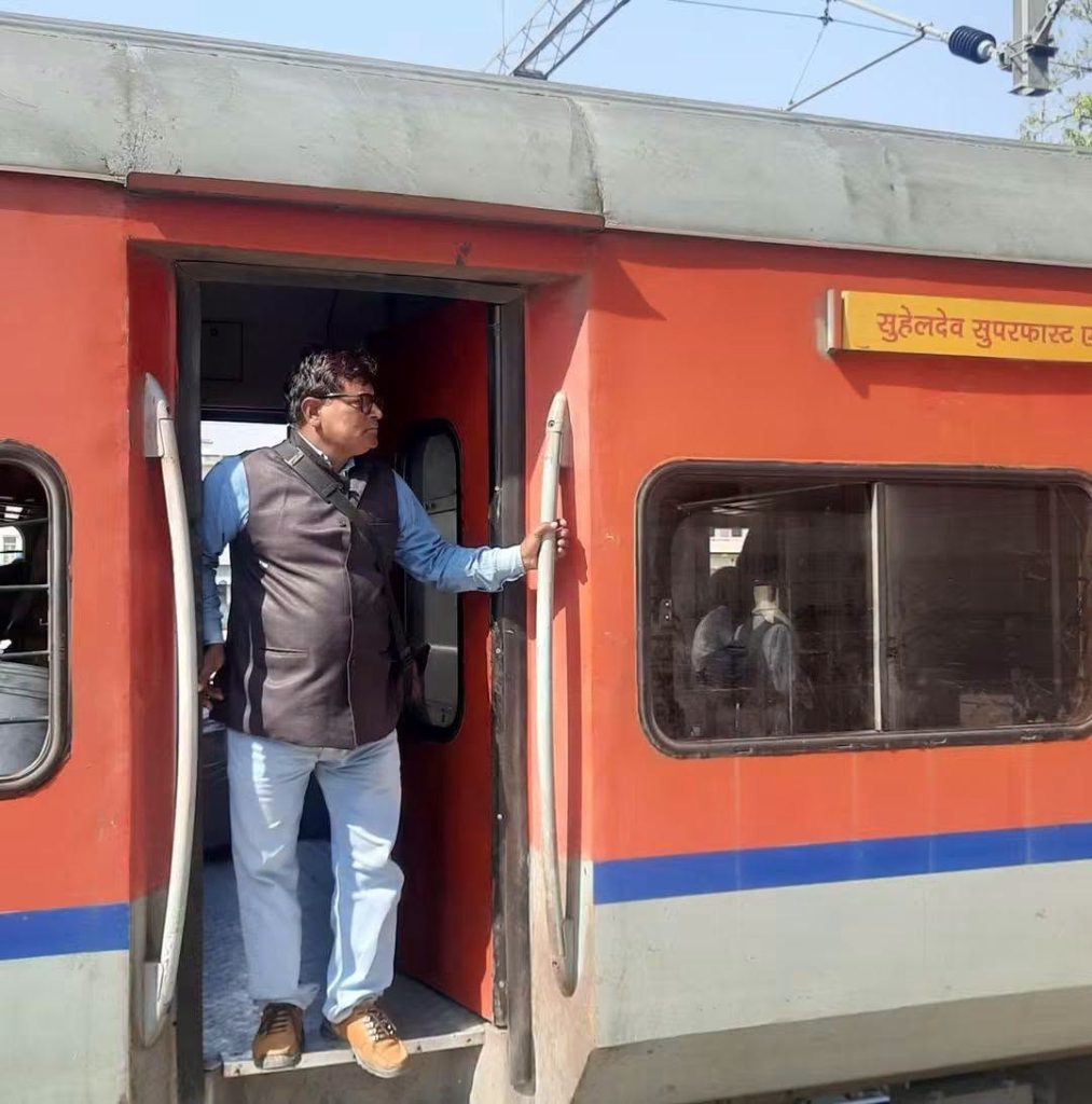 vinay yadav | No. 1 Indian Media News Portal Man in a blue shirt and brown vest stepping off a red train car, holding the door railing.