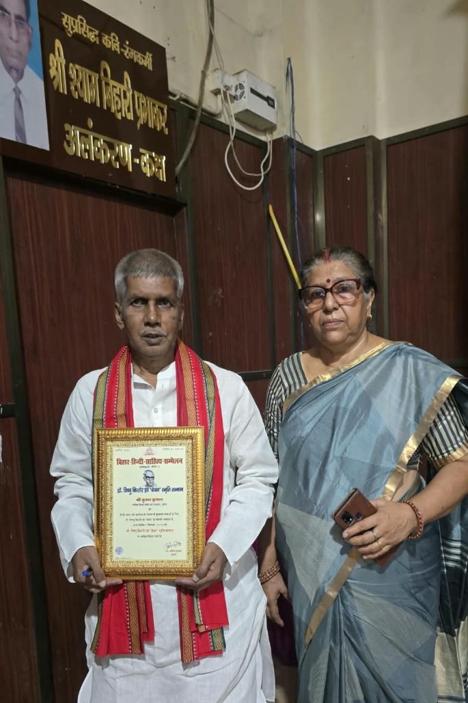 vishnu bechan | No. 1 Indian Media News Portal Man in white kurta with red stole holding a framed certificate, woman in blue sari beside him in an indoor setting with a Hindi sign in the background.