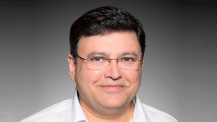 Shailesh Shekhar Sinha | No. 1 Indian Media News Portal Portrait of a man with short dark hair and glasses, smiling against a gray gradient background.