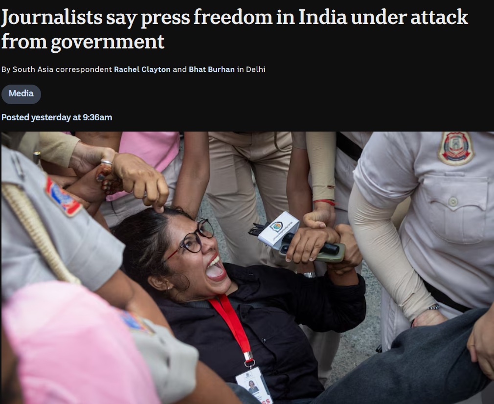 abc news | No. 1 Indian Media News Portal Female journalist with glasses being restrained by security while a microphone is pushed toward her in a crowded scene of reporters and police nearby.