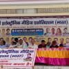 Panel of officials seated at a long table on a stage, with a large Hindi banner and portraits behind them, during a conference.