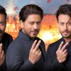 Three men in dark suits pose with peace signs in front of a fireworks-filled festive backdrop.