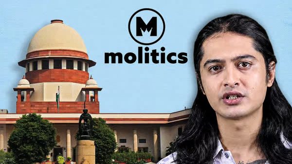Person with long dark hair speaking, positioned in front of a domed government building, with the Molitics logo above.