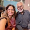 Two people smiling for a selfie at an event, with a blue backdrop reading 'The Moment of Lift Summit & Awards'.
