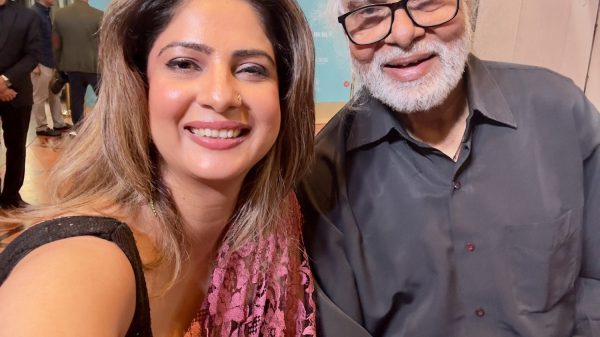 Two people smiling for a selfie at an event, with a blue backdrop reading 'The Moment of Lift Summit & Awards'.
