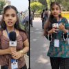 Two young female reporters stand on a city street, each holding a microphone with a news logo and wearing ID badges in front of a crowd.