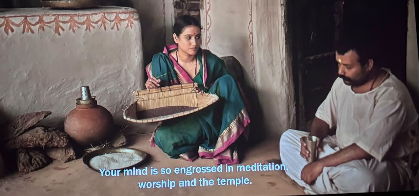 hanuman ansh | No. 1 Indian Media News Portal Woman in a teal saree with pink border sits cross‑legged holding a woven basket, inside a rustic room with pottery nearby.