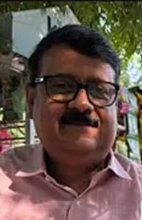 image-1 | No. 1 Indian Media News Portal Portrait of a man with glasses and a mustache wearing a pink shirt, smiling outdoors among trees.