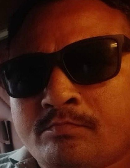 Close-up of a man wearing dark sunglasses and a mustache, looking at the camera.
