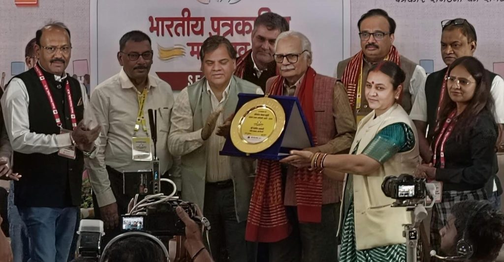 img_1778 | No. 1 Indian Media News Portal Group of people on a stage presenting a circular gold-plated award in a blue case.