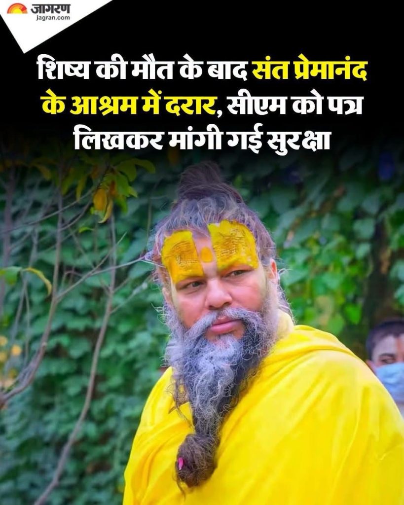 Bearded man in bright yellow robe with yellow forehead tilak, standing outdoors among greenery; appears to be a spiritual ascetic.