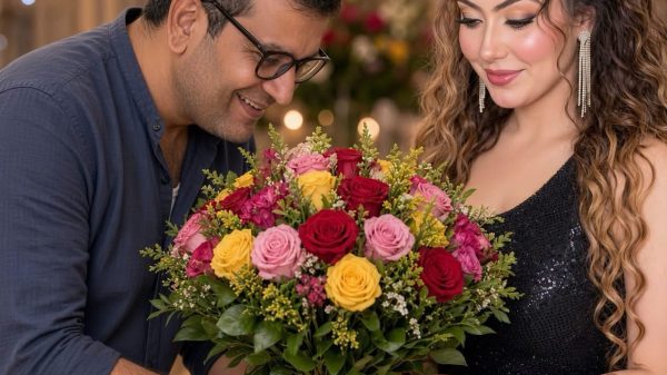A man and a woman in formal attire hold a colorful bouquet of roses together.