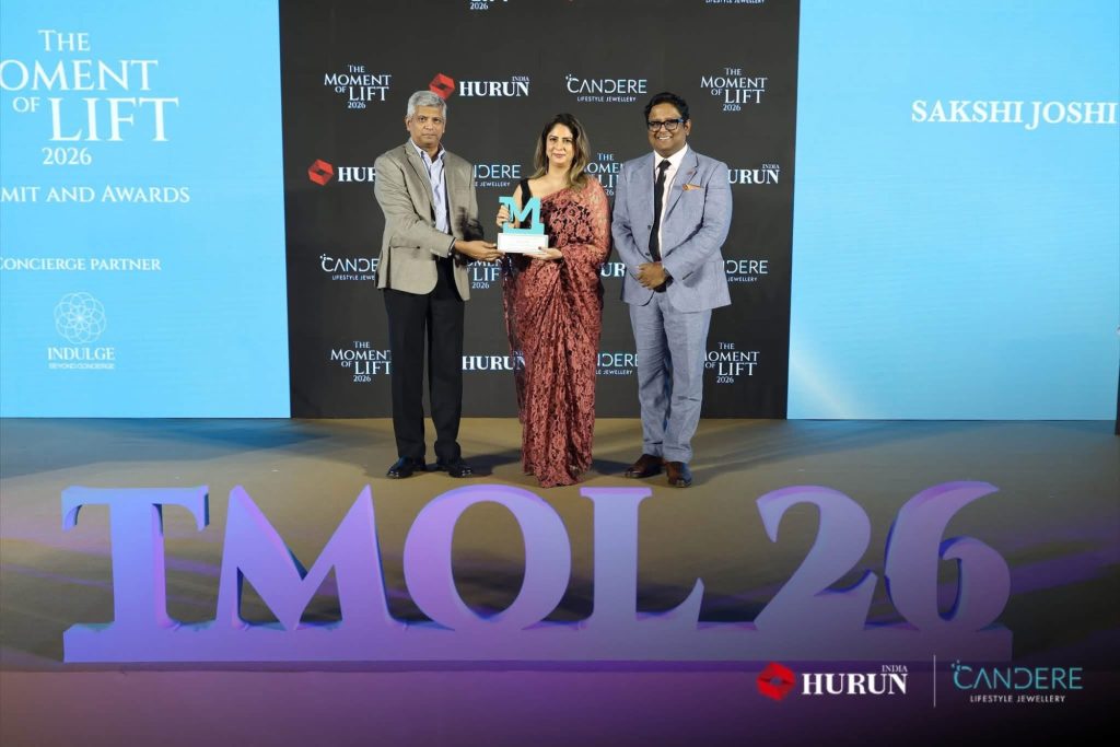 img_2395 | No. 1 Indian Media News Portal Three people in formal attire posing with an award on a stage, backdrop reads 'The Moment of Lift 2026' with sponsor logos.