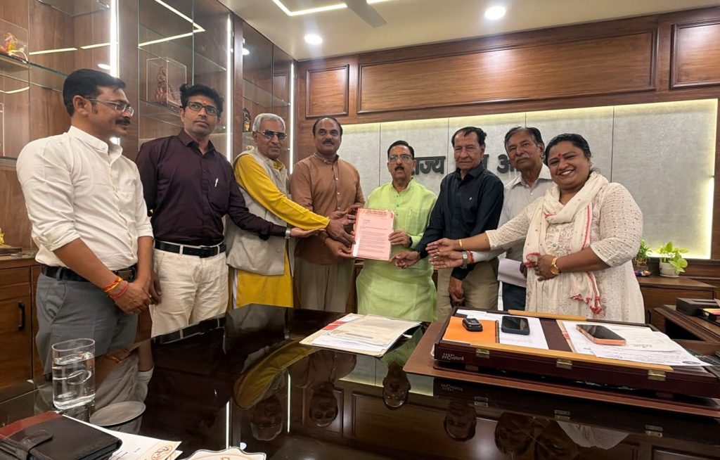 jaipur | No. 1 Indian Media News Portal Eight people stand around a glossy office desk as they jointly hold a red document, smiling for the camera.