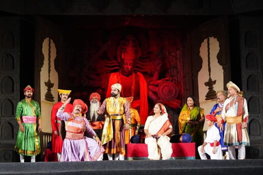 janta raja | No. 1 Indian Media News Portal Group of actors in colorful Indian costumes performing on a stage with a red deity backdrop behind them.