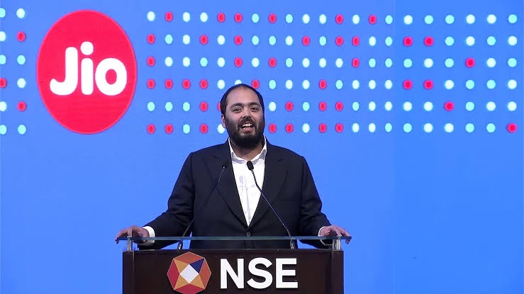 Speaker in a dark suit delivering a speech at a podium labeled NSE, with a Jio logo backdrop.