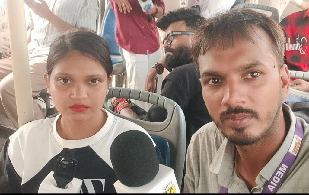 jitesh | No. 1 Indian Media News Portal Woman being interviewed on a bus holds a large microphone toward camera, with a man beside her and passengers in the background.