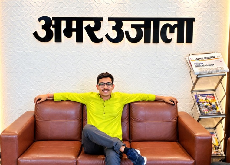 kishan chaubey | No. 1 Indian Media News Portal Man in a lime shirt lounging with arms on a brown leather sofa beneath an Amar Ujala sign; a newspaper rack sits to the right.