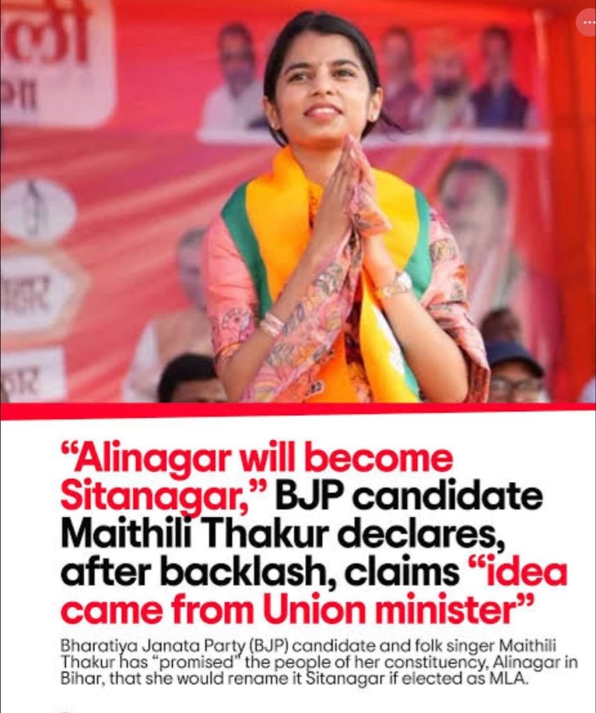 Screenshot | No. 1 Indian Media News Portal Woman candidate on stage with hands pressed together in greeting, wearing an orange scarf over colorful attire, against a red campaign backdrop with bold political text in the foreground.